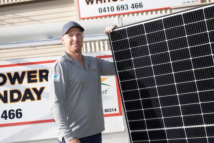 A Man Standing With A Solar Panel In Front Of Our Signage — Solar Power Whitsunday In Cannon Valley, QLD