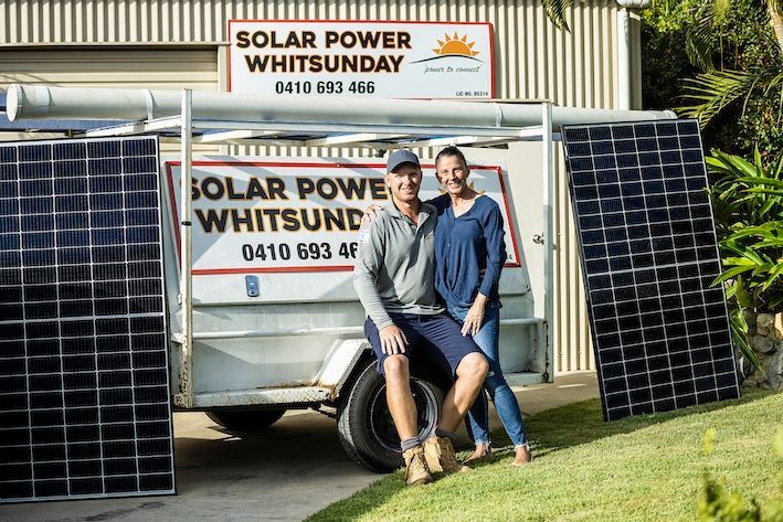A Woman and A Man Are Standing In Front Of A Trailer That Says Solar Power Whitsunday — Solar Power Whitsunday In Cannon Valley, QLD
