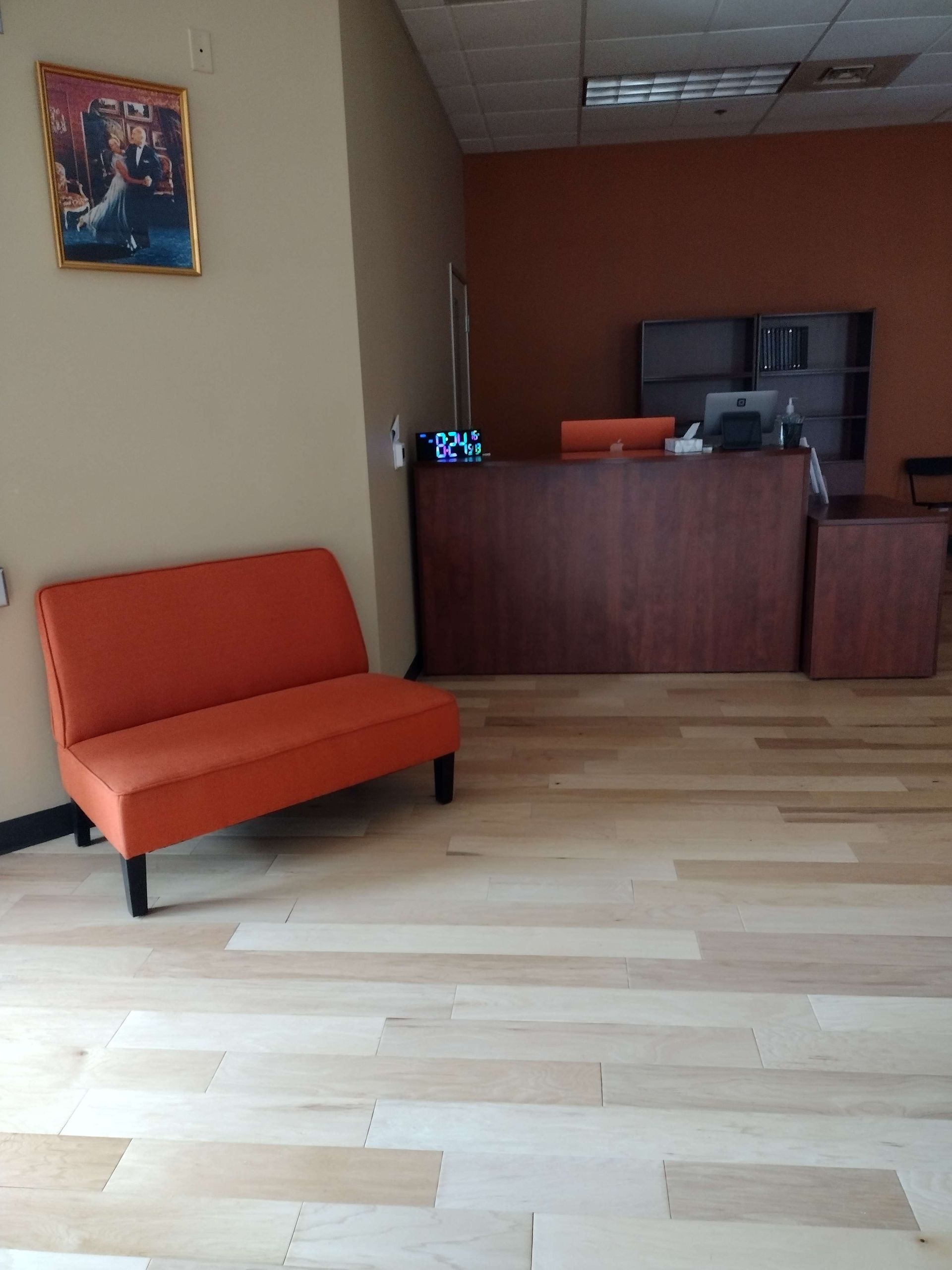 A wooden crate holding a paint tray with brushes sits on the floor before a partially painted orange wall with a roller.