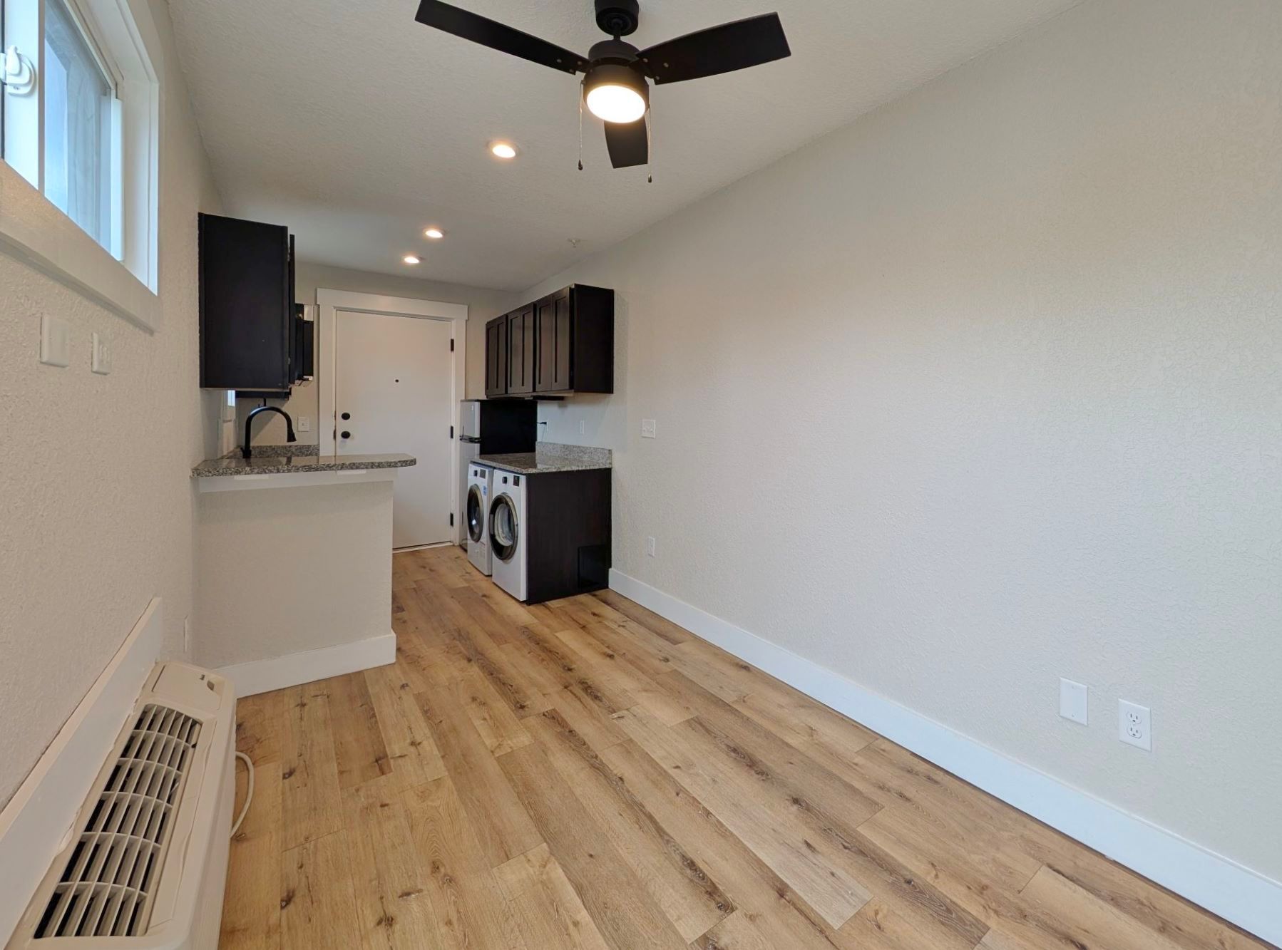 Small apartment interior with kitchen, laundry, and hardwood floors.