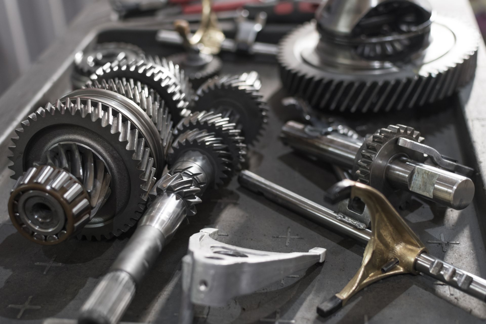 Gears, shafts, and other transmission parts laid out on a tray, likely for repair or inspection.