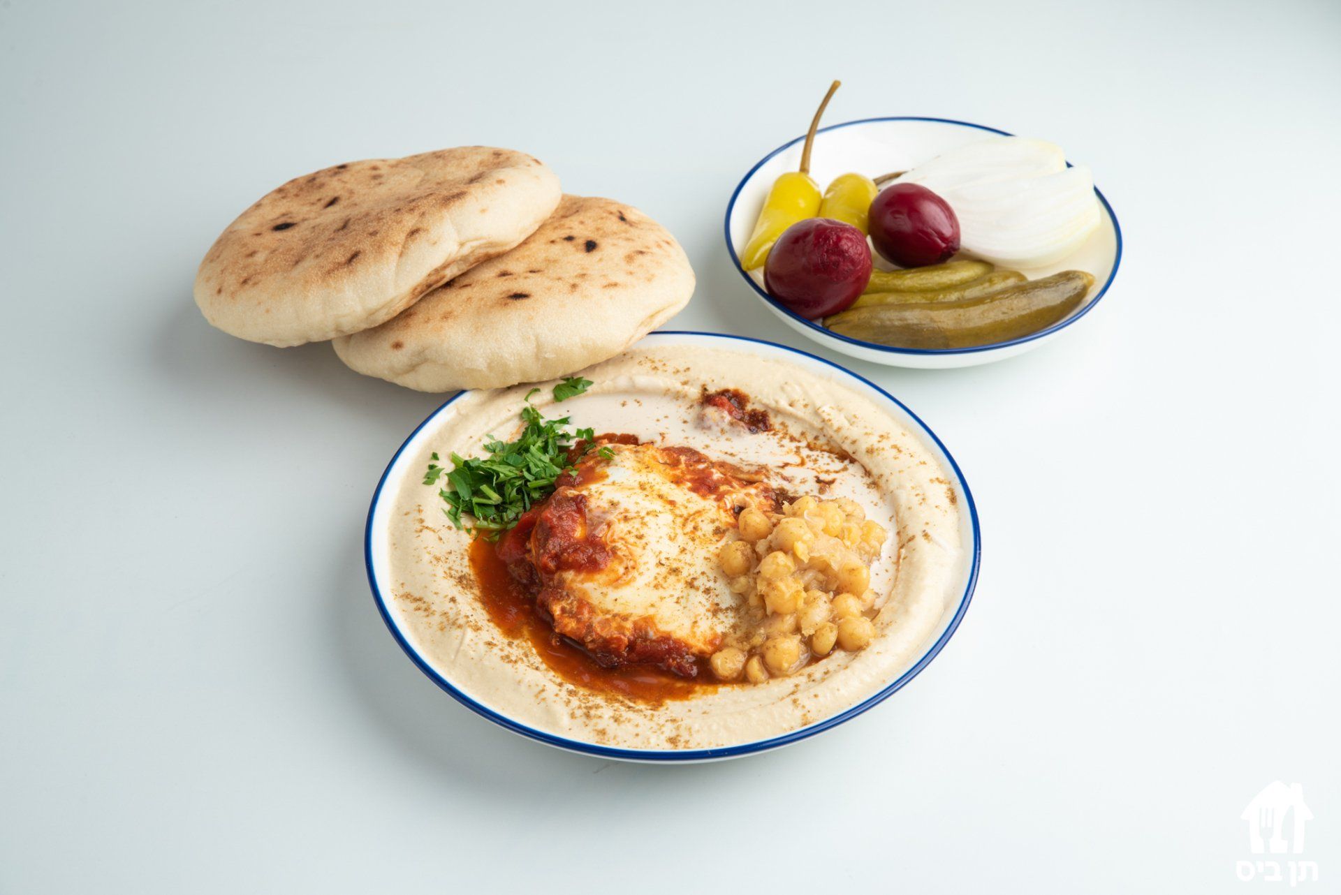 צלחת אוכל עם פיתות וחמוצים על שולחן.