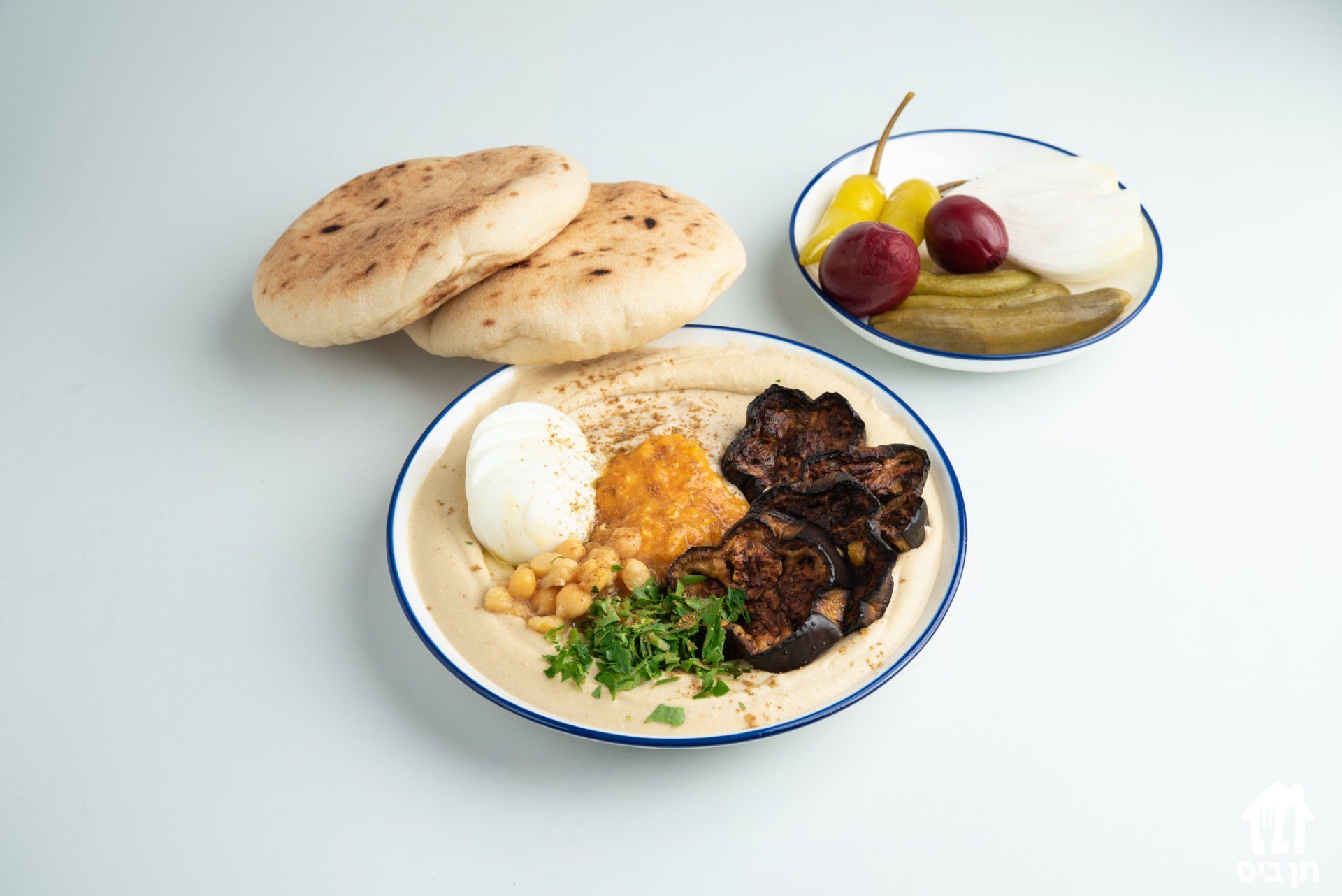 צלחת אוכל עם פיתות וחמוצים על שולחן.