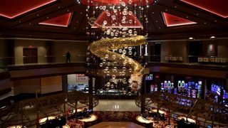 Interior of a casino or hotel atrium with a large spiral chandelier and slot machines below
