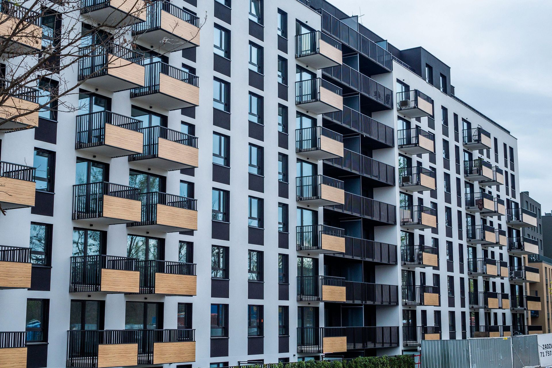 Modern apartment buildings with balconies and large windows under a cloudy sky