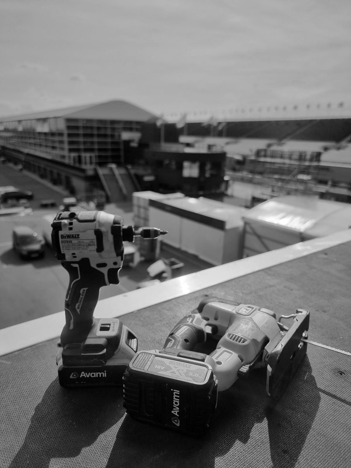Impact driver and jigsaw on a rooftop, with a race track and grandstand in the background.