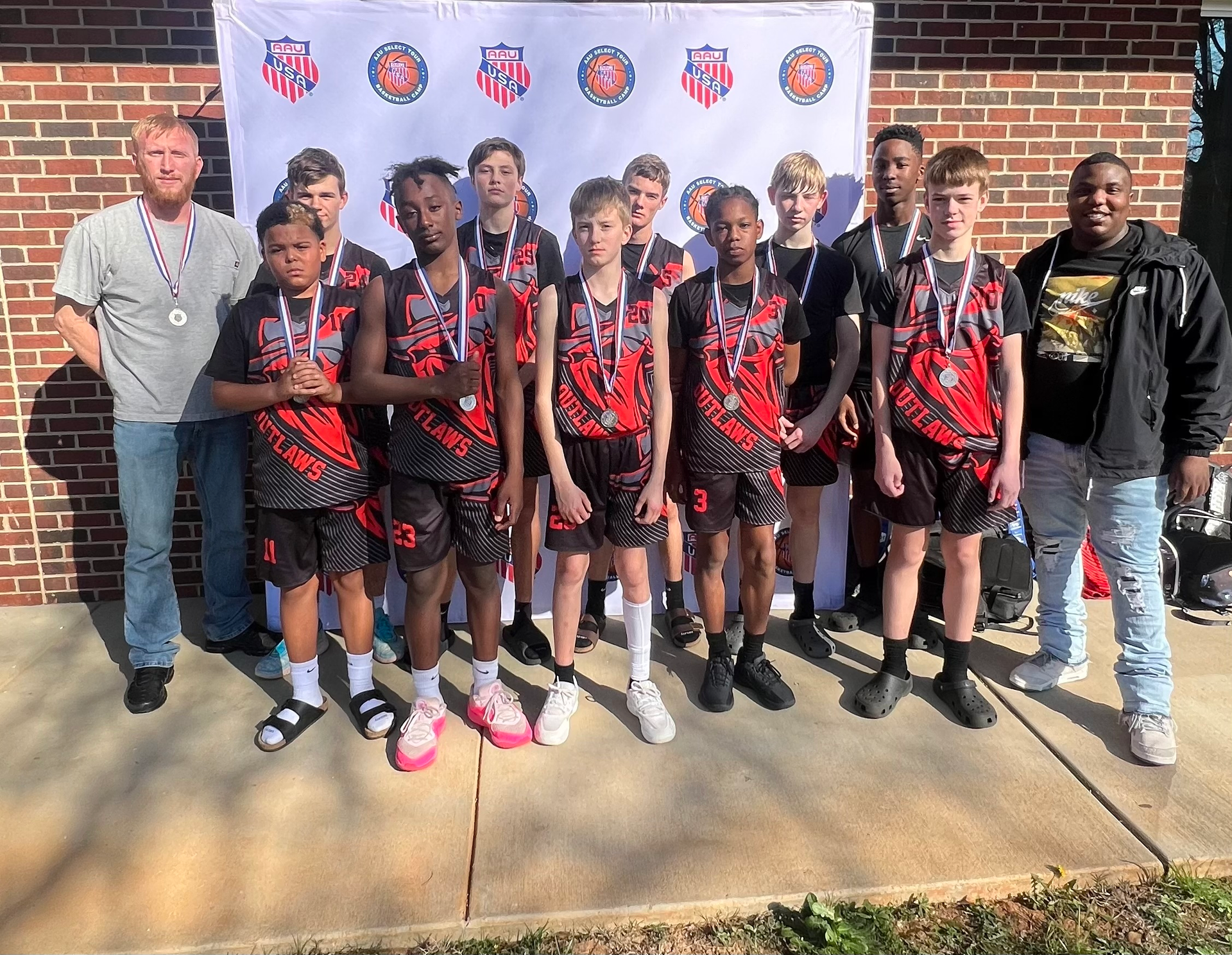A group of young men are posing for a picture in front of a brick building.