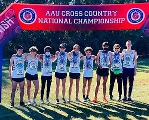 A group of people are standing in front of a sign that says aau cross country national championship.