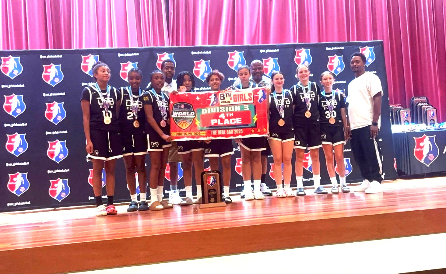 Two young girls are playing basketball on a court.