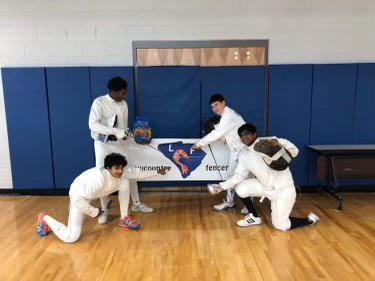 A group of young men in fencing uniforms are posing for a picture.