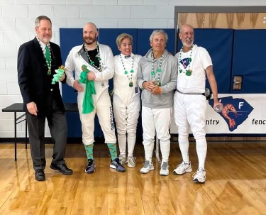 A group of people in fencing uniforms are posing for a picture