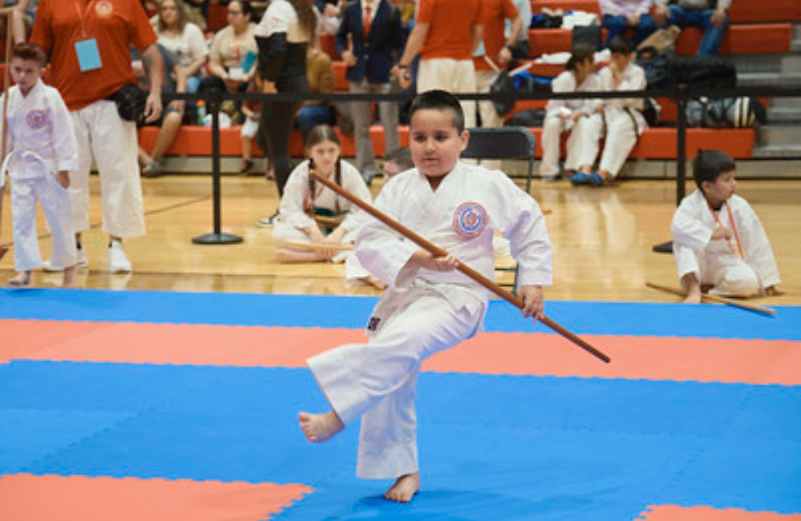 A young boy is practicing martial arts with a stick.