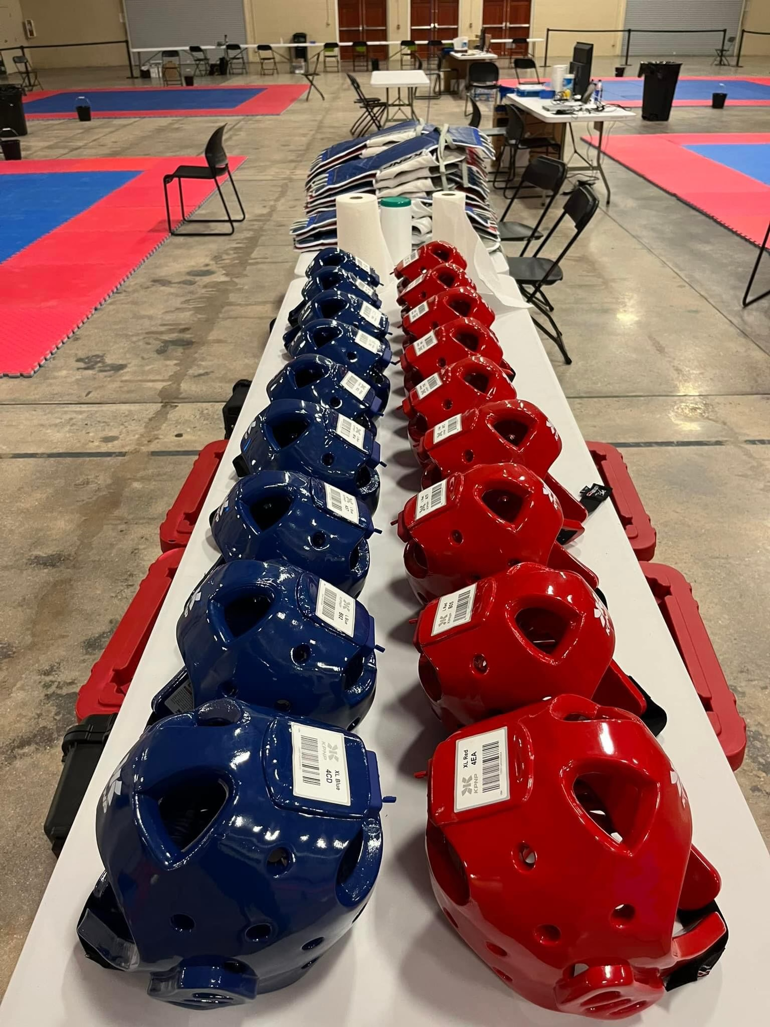 A row of blue and red helmets are lined up on a table.