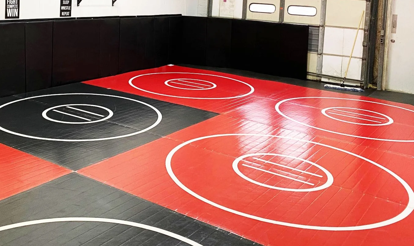 A red and black wrestling mat with white circles on it.