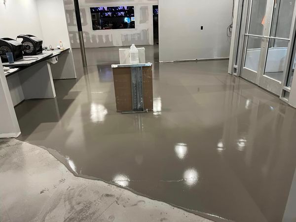 worker pouring gray epoxy resin to the floor