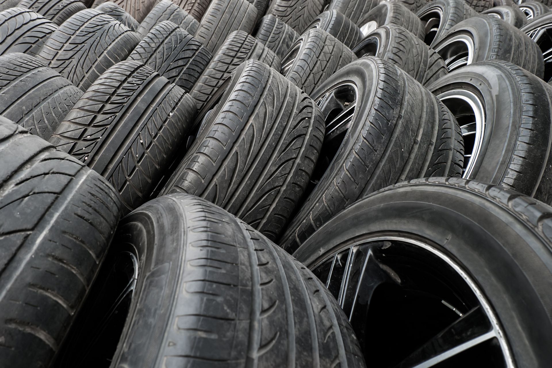 A pile of tires and wheels are stacked on top of each other.
