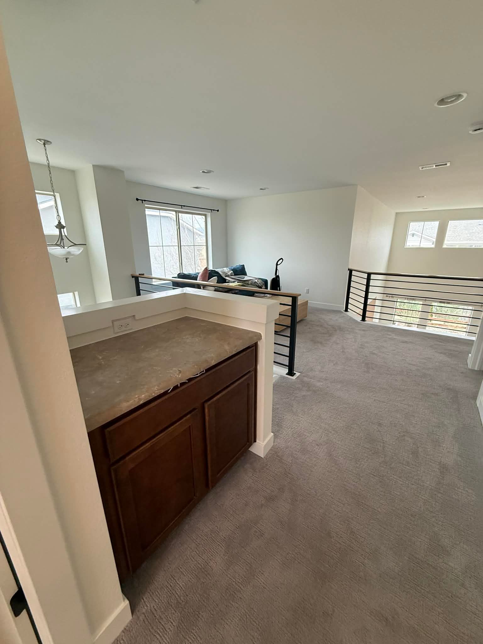 Empty carpeted living room with kitchen island, dark wood cabinets, and patterned wall paneling