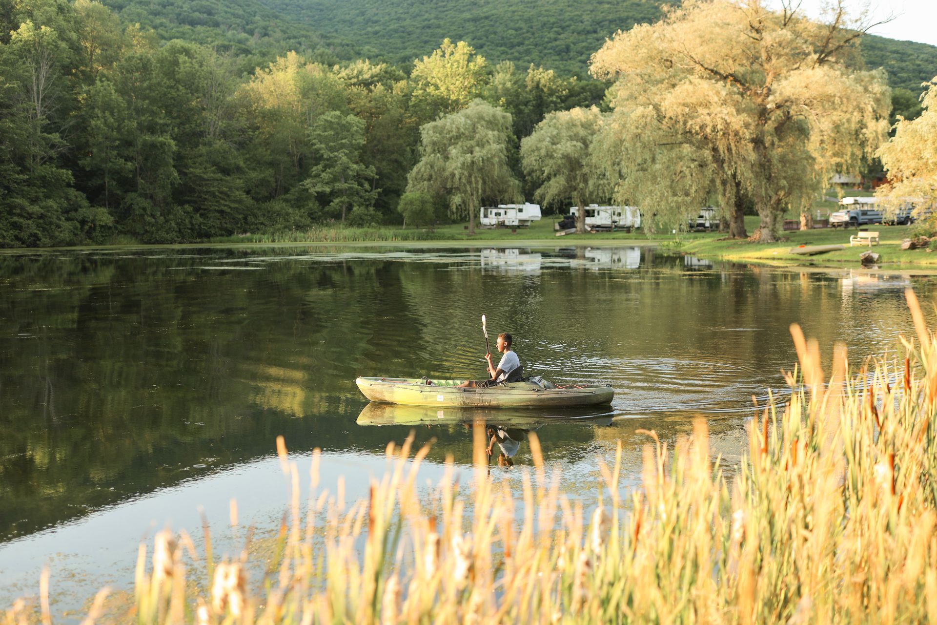 A man is paddling a kayak on a lake.