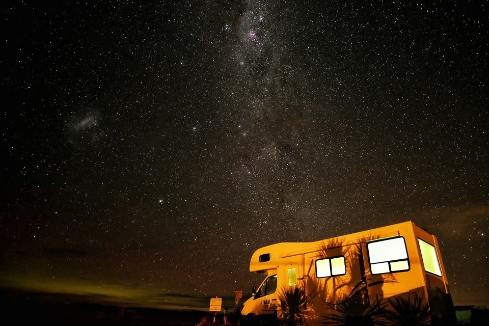 A rv is parked under a starry night sky