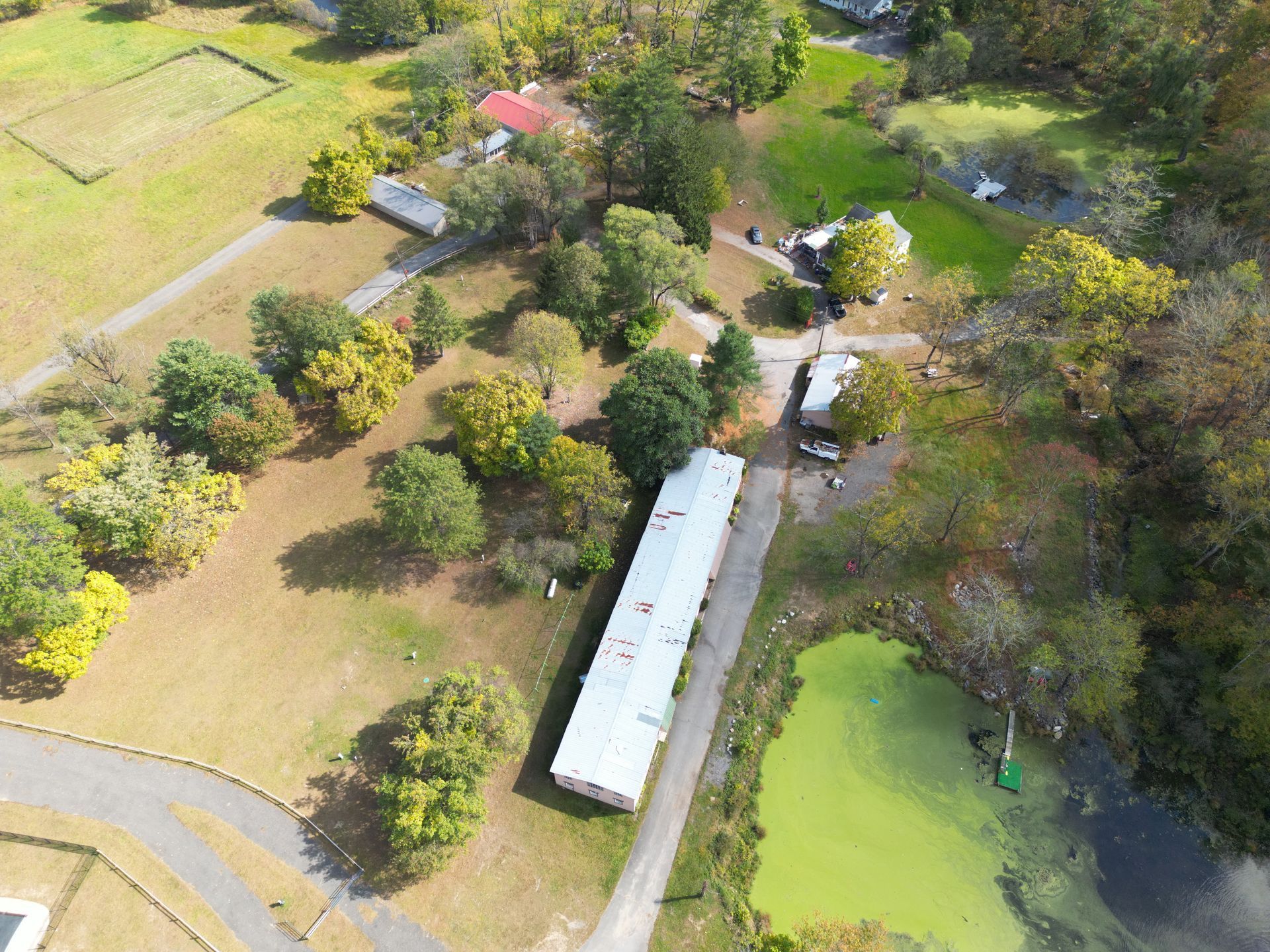 An aerial view of a house in the middle of a field surrounded by trees.