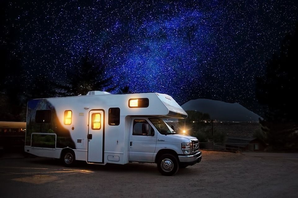 A white rv is parked under a starry night sky.