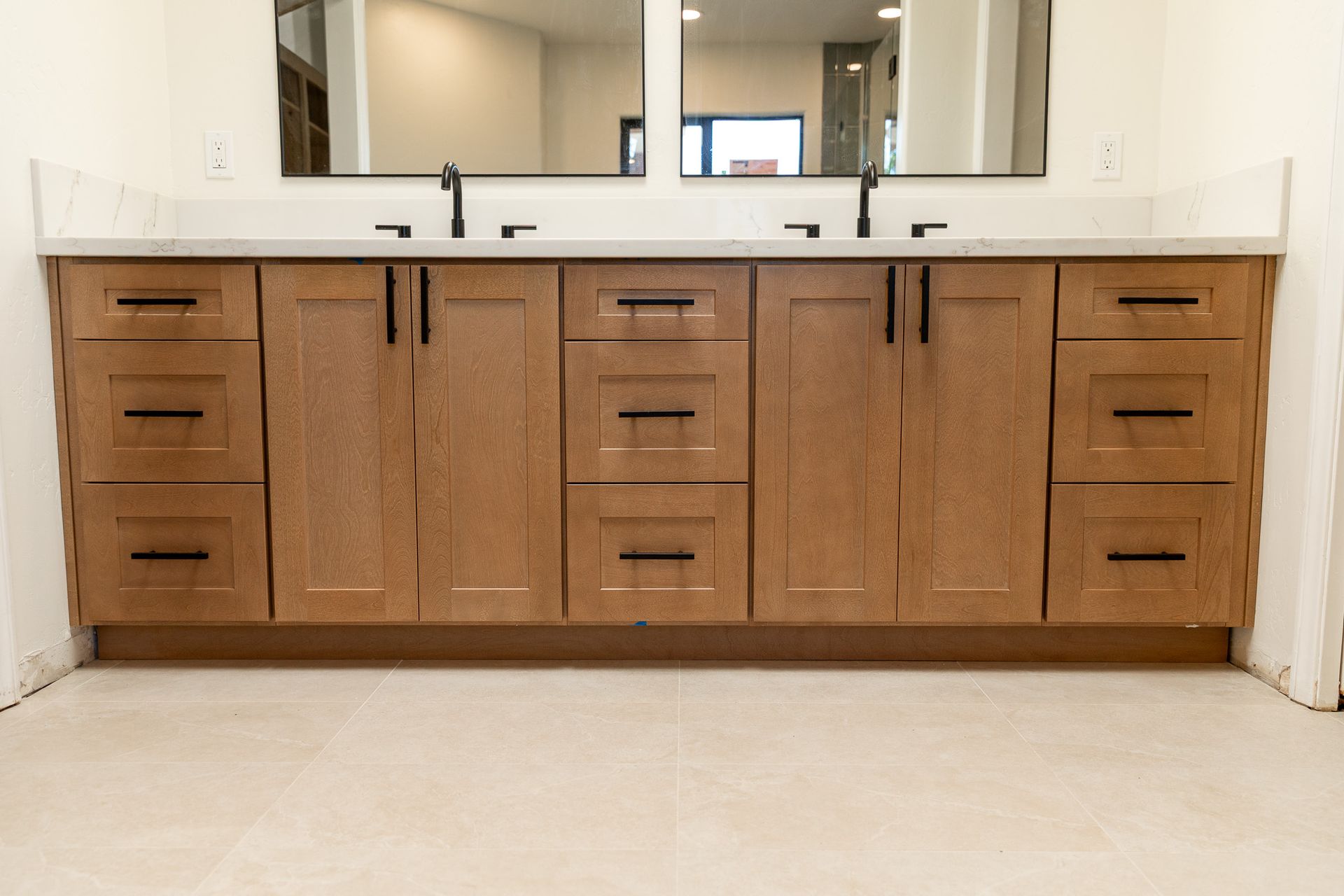 A shower with gray tiles and a black shower head.