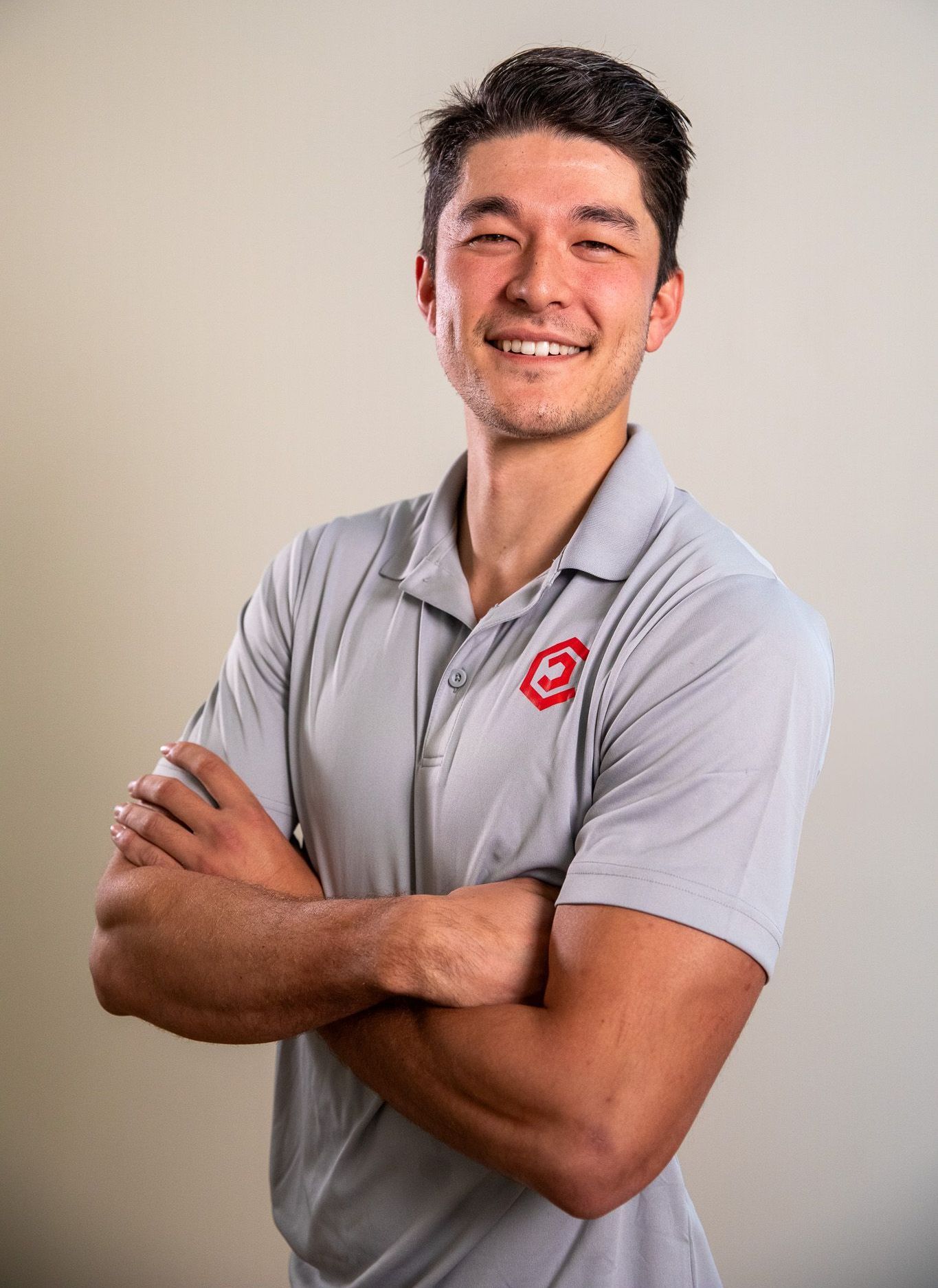 Luc Neesby is in a Center Home Improvement shirt standing with his arms crossed and smiling.