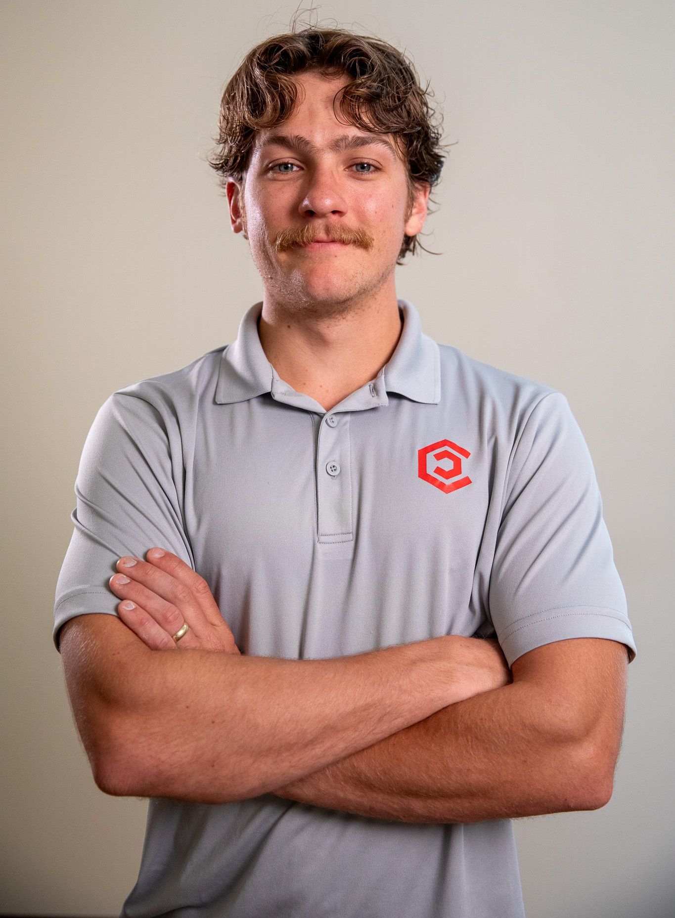 Spencer Fowler is in a Center Home Improvement shirt standing with his arms crossed and smiling.