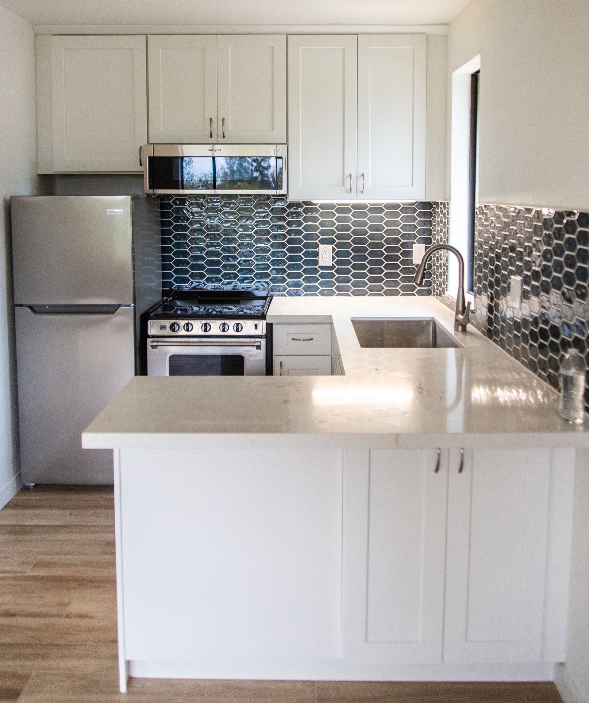 A remodeled ADU kitchen with white cabinets and stainless steel appliances