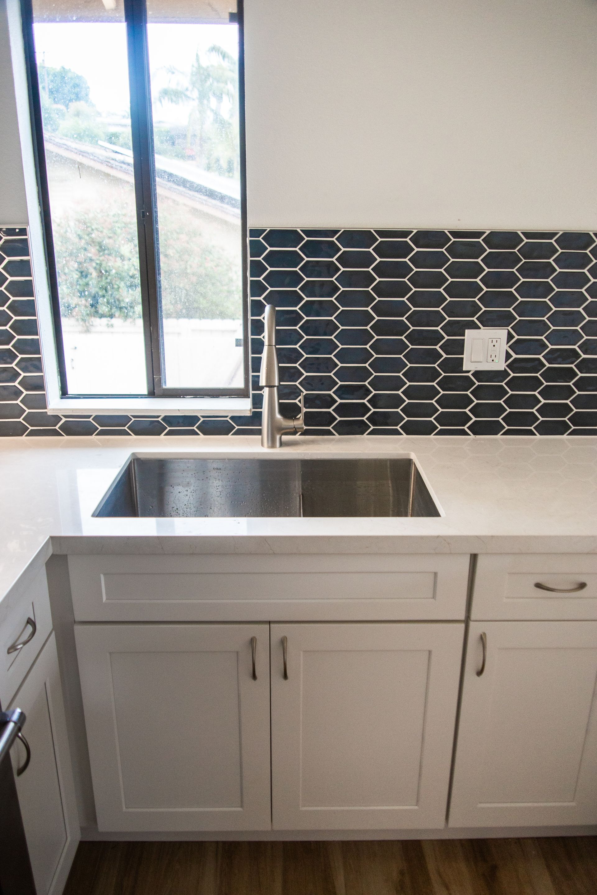 A remodeled ADU kitchen with a sink, cabinets, and a window.