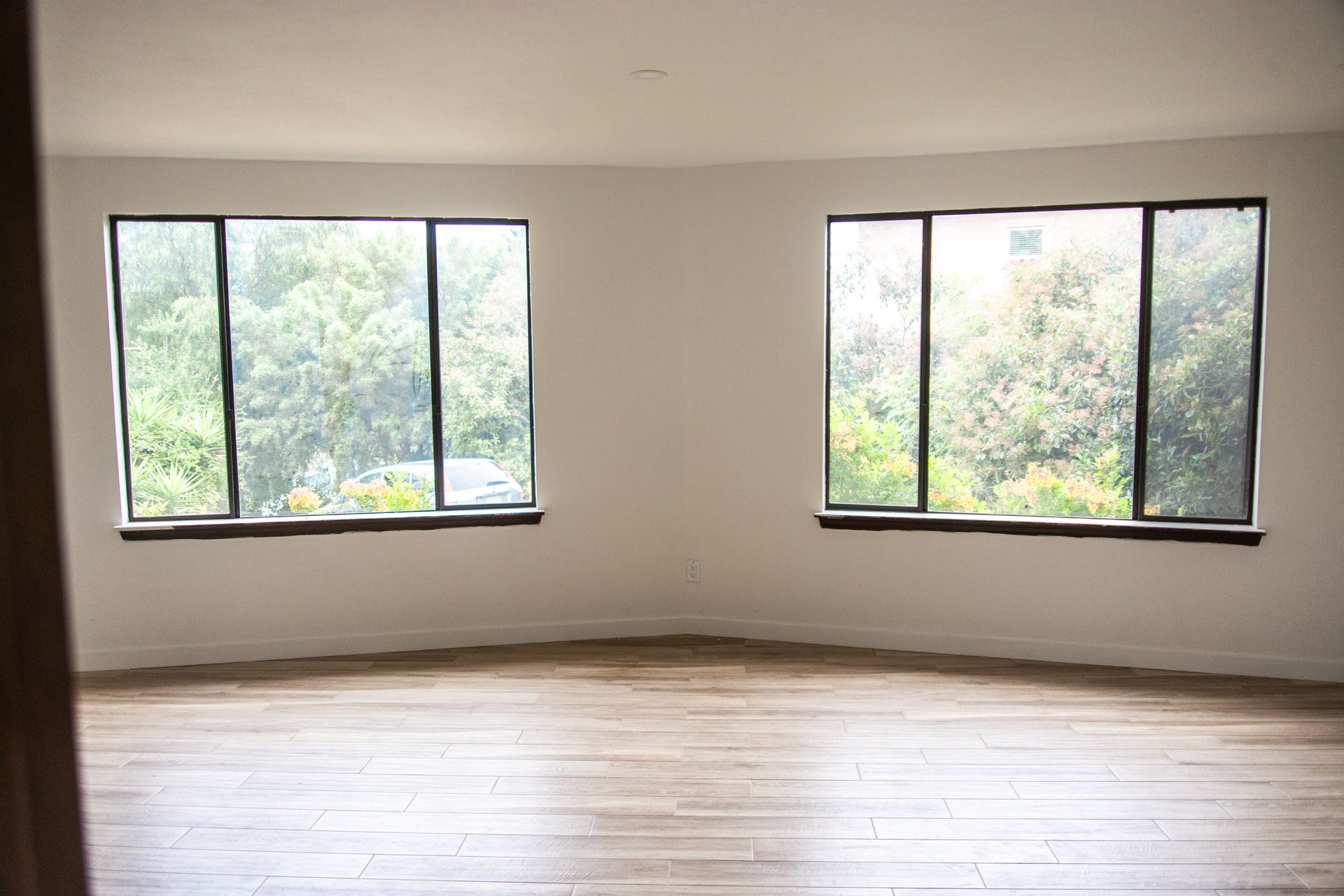 A remodeled ADU living room with two windows and a wooden floor.