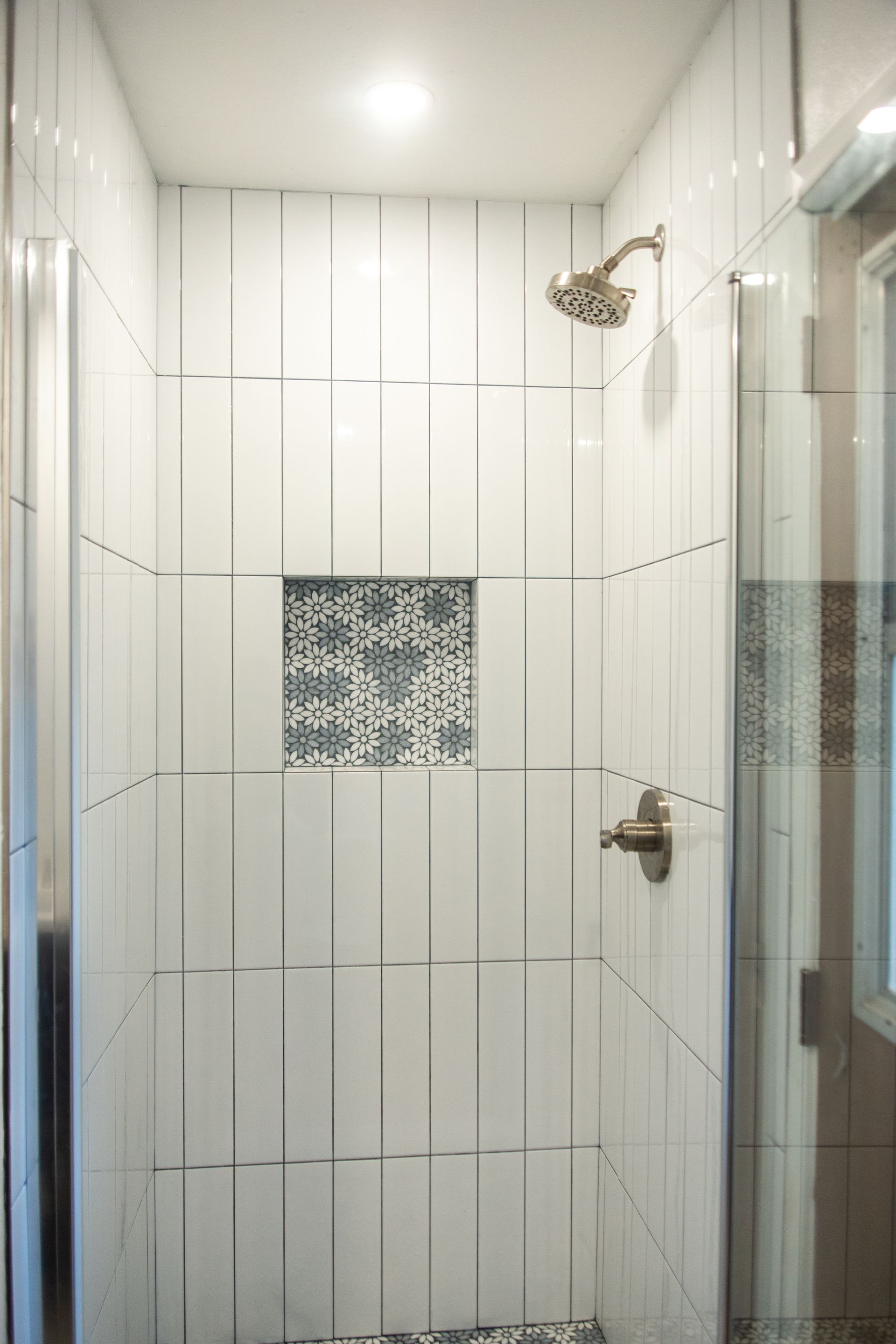 An ADU shower remodel with white tiles and a shower head.