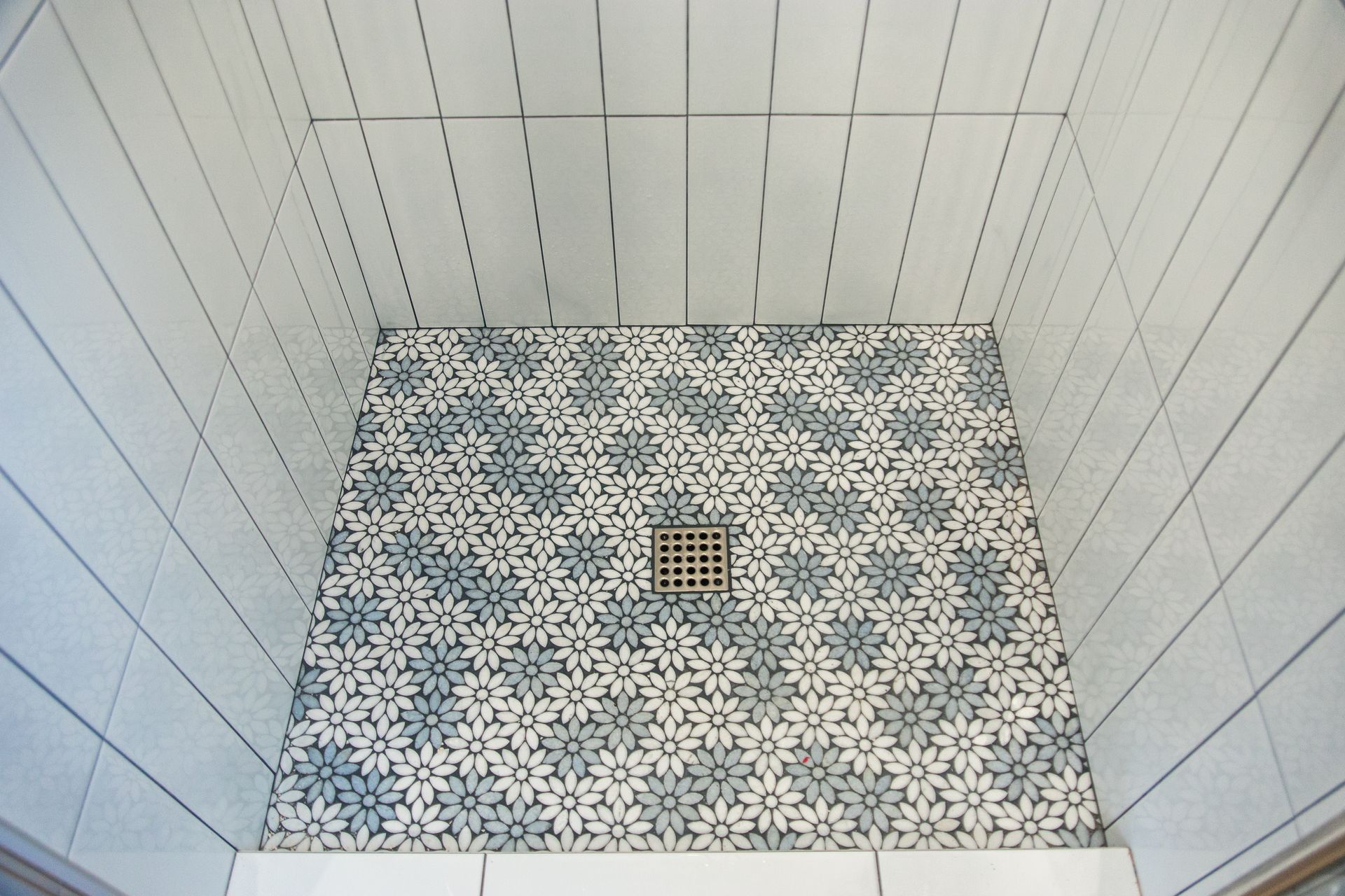 An ADU shower remodel with white tiles and a drain on the floor