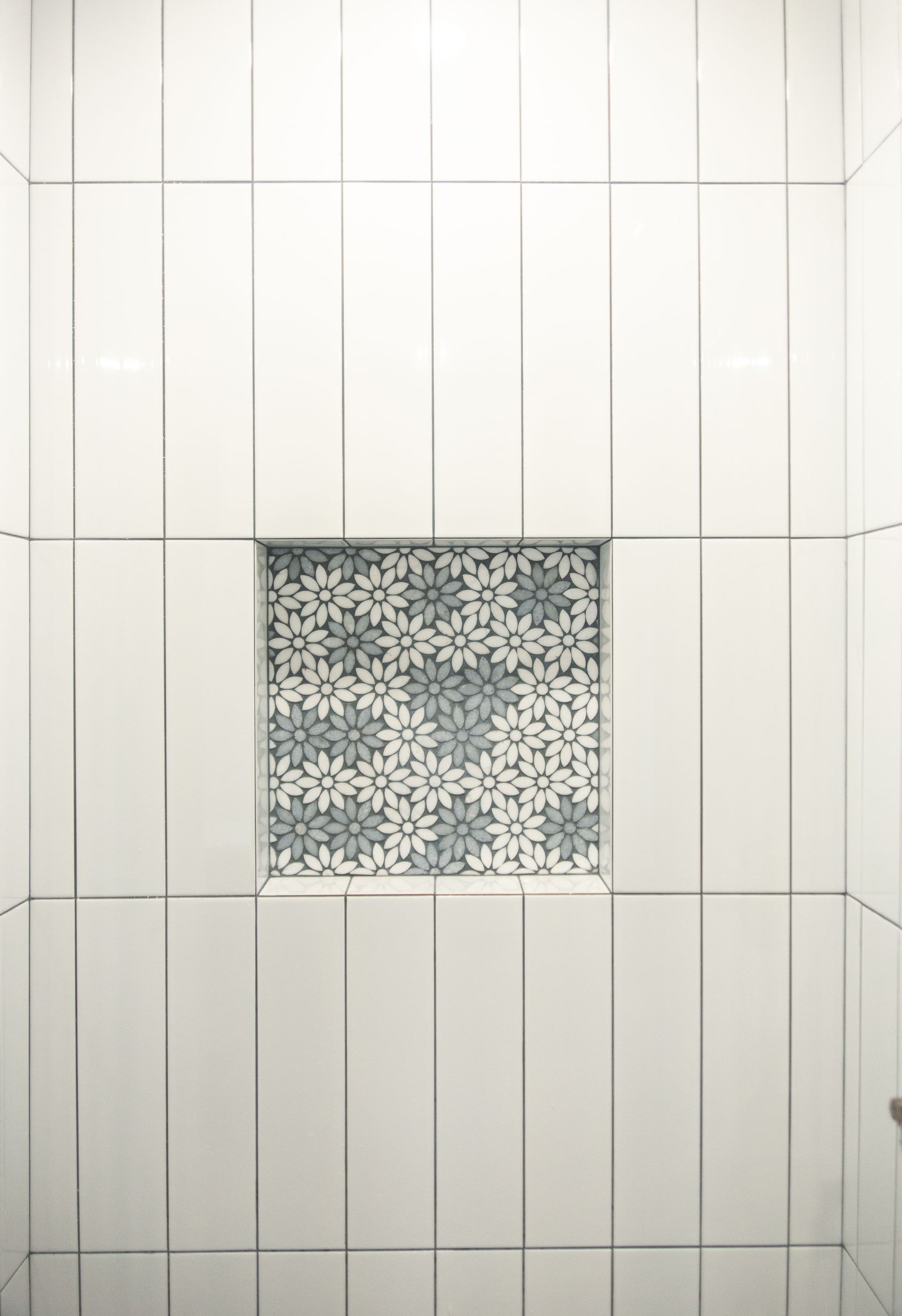 A bathroom with white tiles and a niche in the wall.