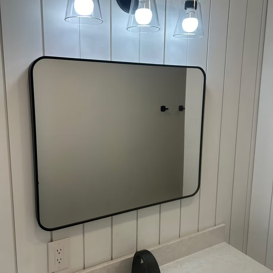 A bathroom mirror is hanging on the wall above a sink.