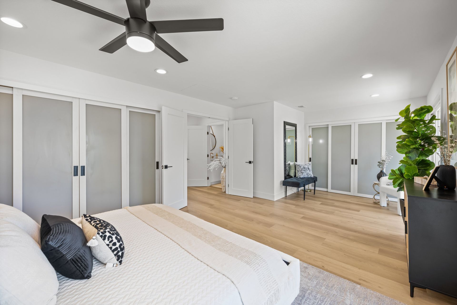 A remodeled bedroom with a large bed, a ceiling fan, and newly replaced doors.
