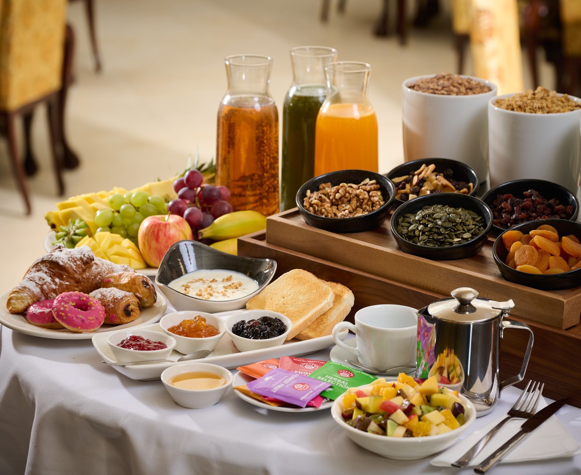 People enjoying breakfast at a table with orange juice, coffee, croissants, and plates of food.