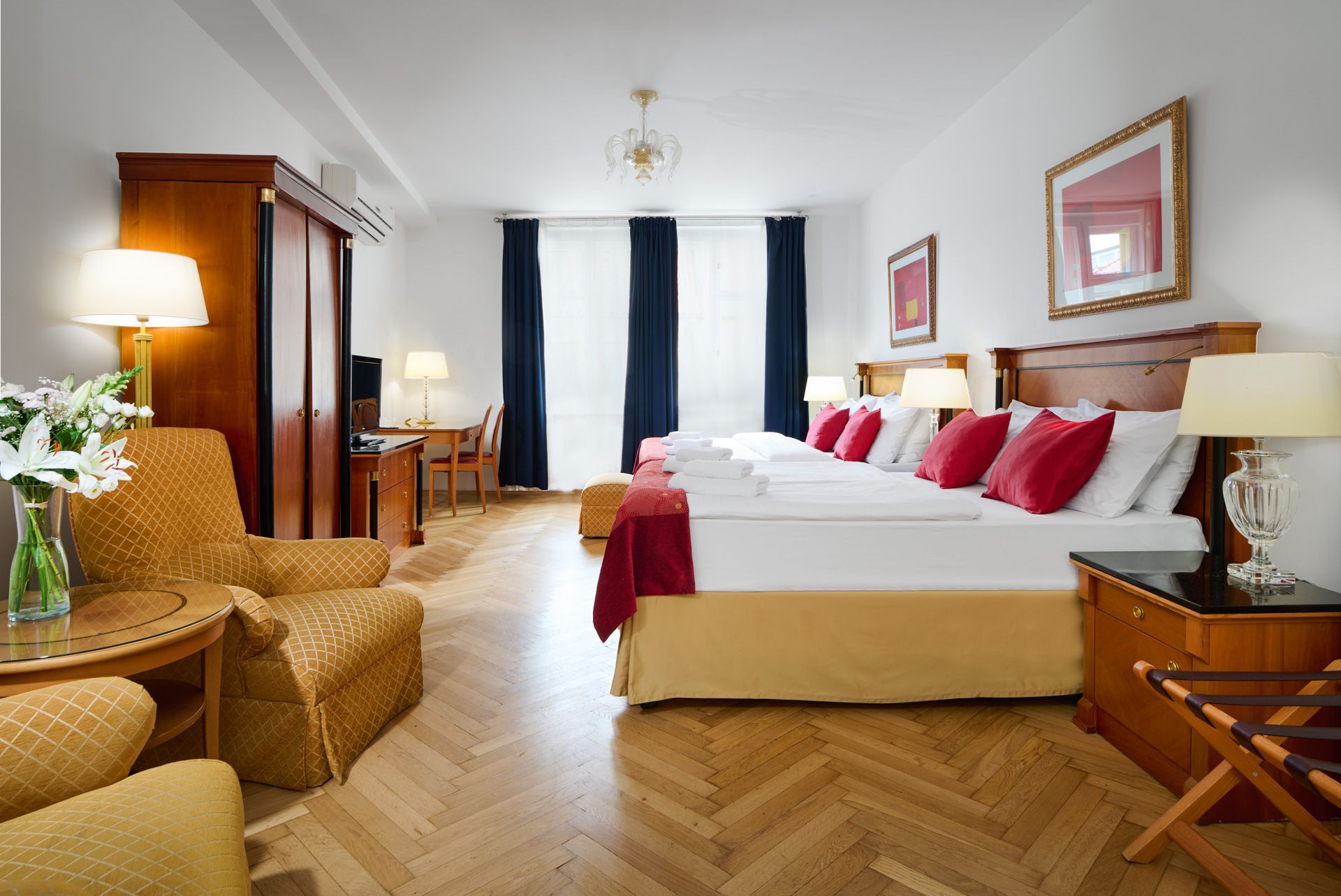 Two yellow armchairs face a window with sheer curtains, two beds on either side.