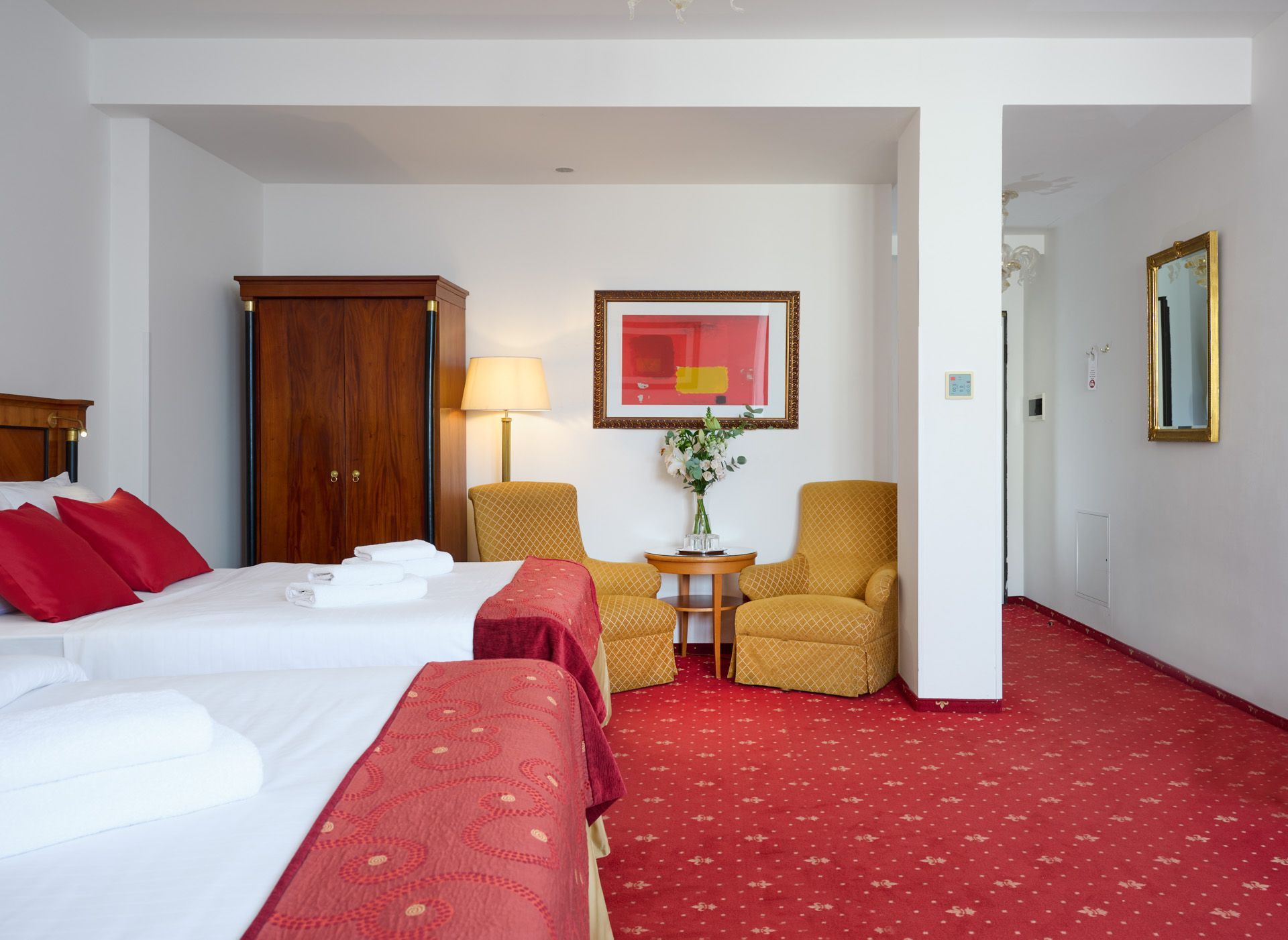 Hotel room with two double beds, red carpet, desk, and window with curtains.