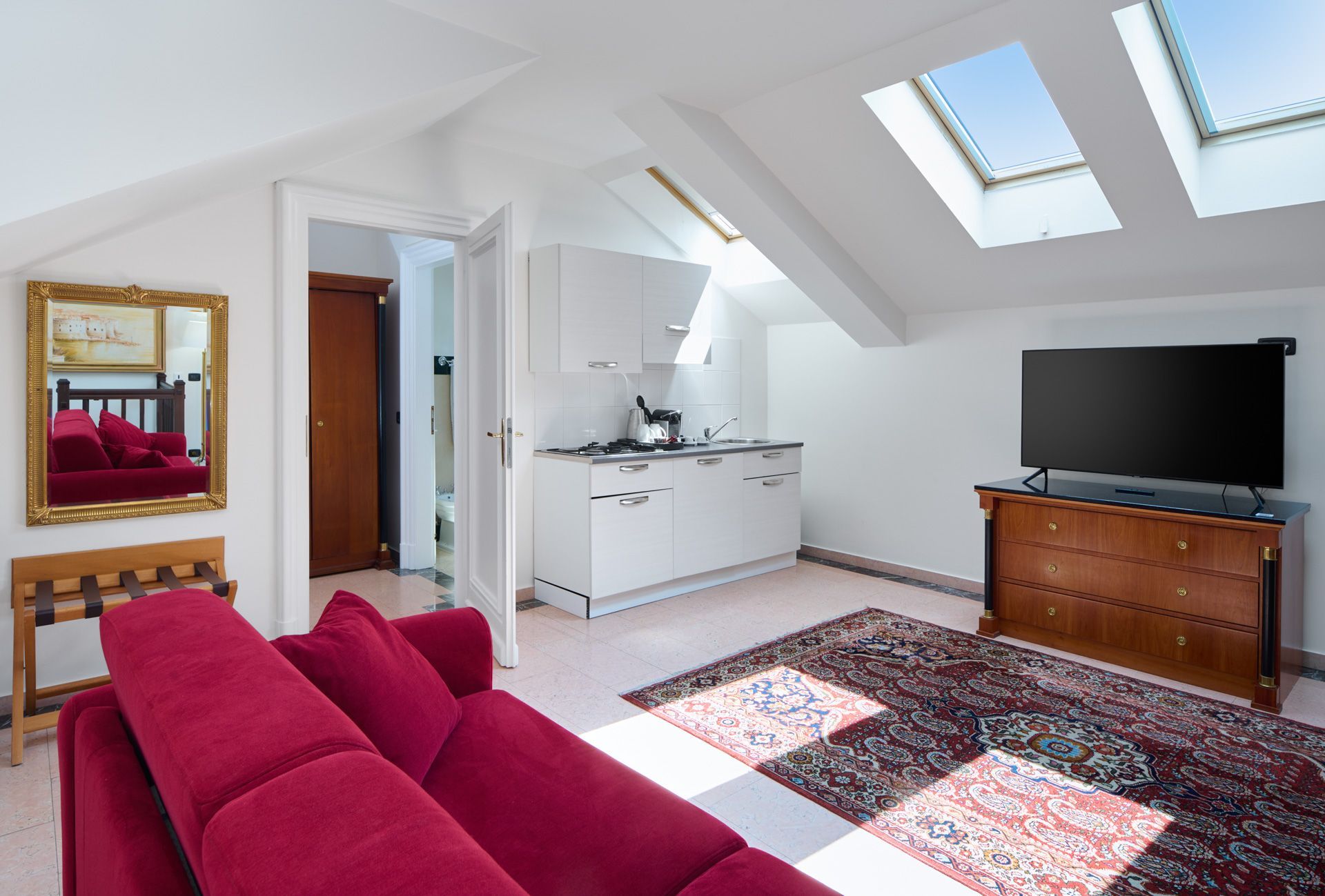 Hotel room with two beds, red carpet, and an adjoining room with a bed.