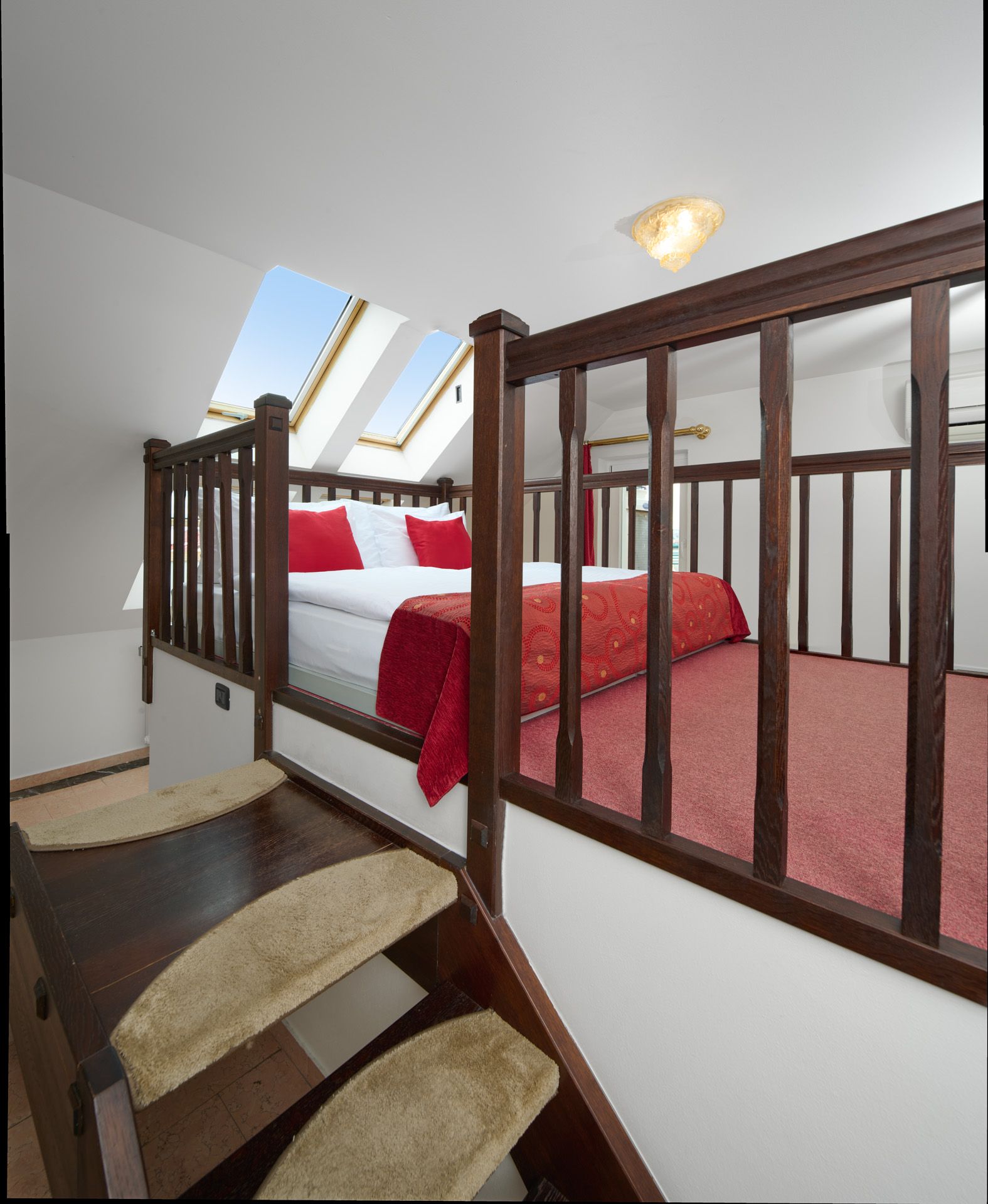 Hotel room with three beds, red bedding, colorful city mural on wall, red carpet.