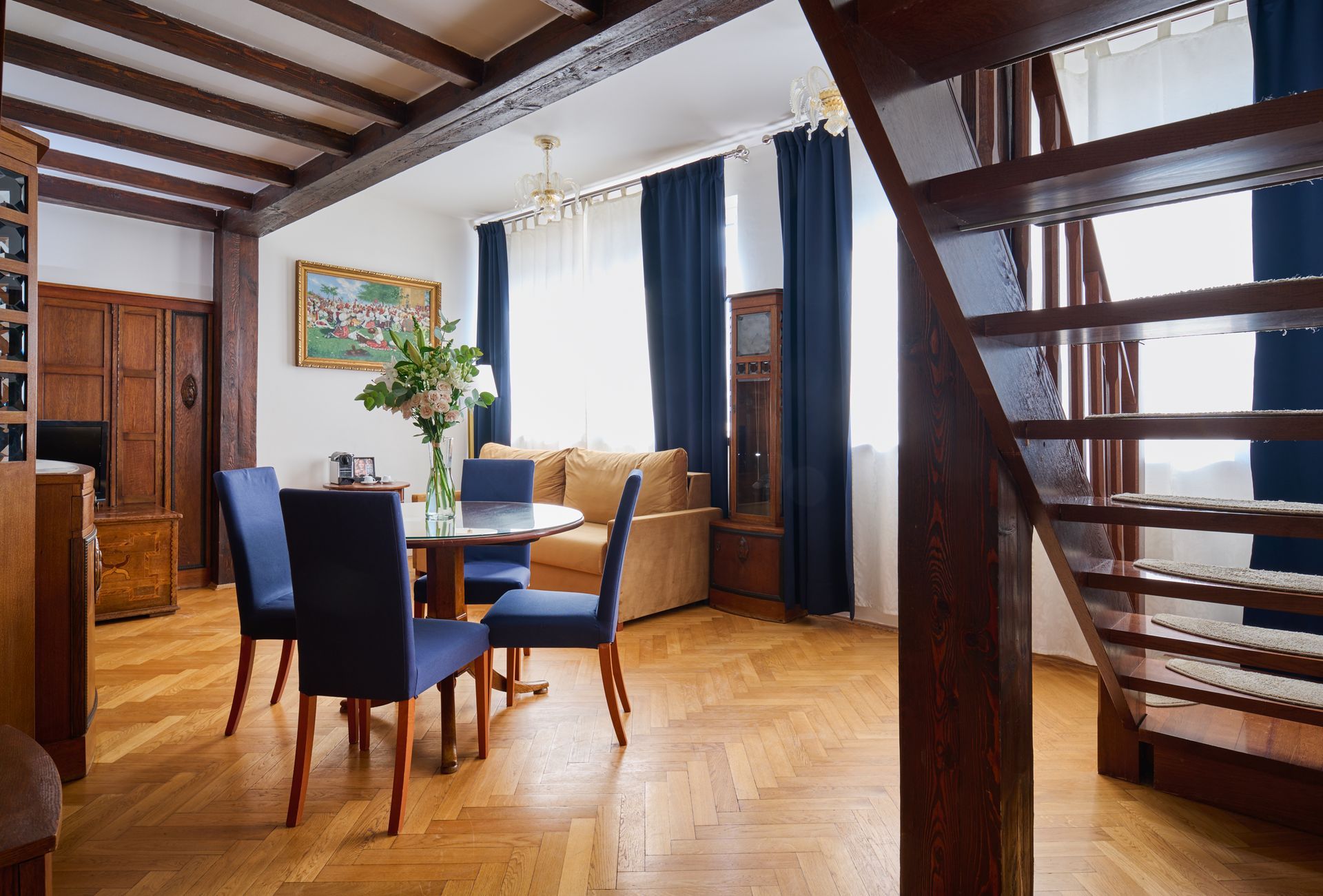 Living room with red carpet, red sofa, blue chairs, and an open doorway to a small kitchen.