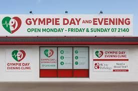 Sign for Gympie Day and Evening Clinic, white building with red trim, green heart logo.