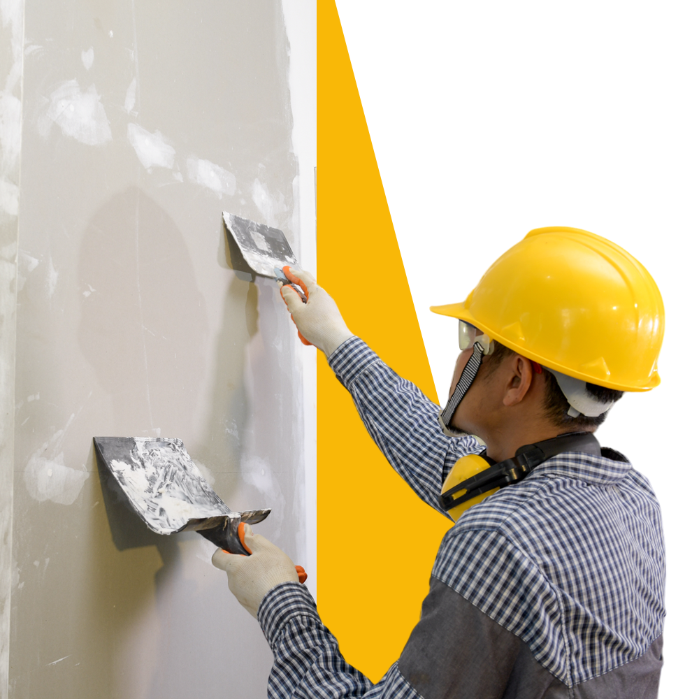 A man wearing a hard hat is plastering a wall with a spatula.