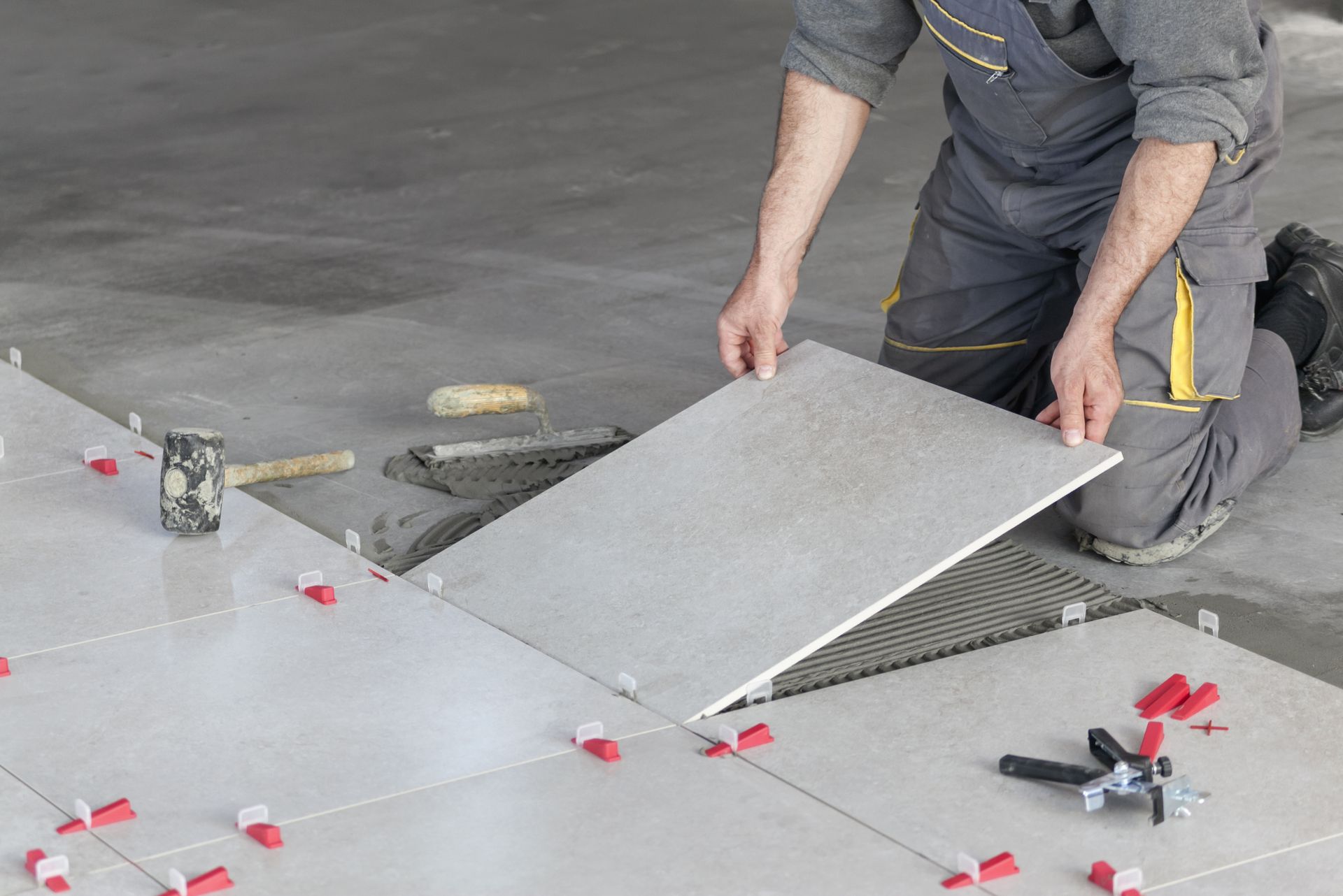 A man is laying a tile on the floor.