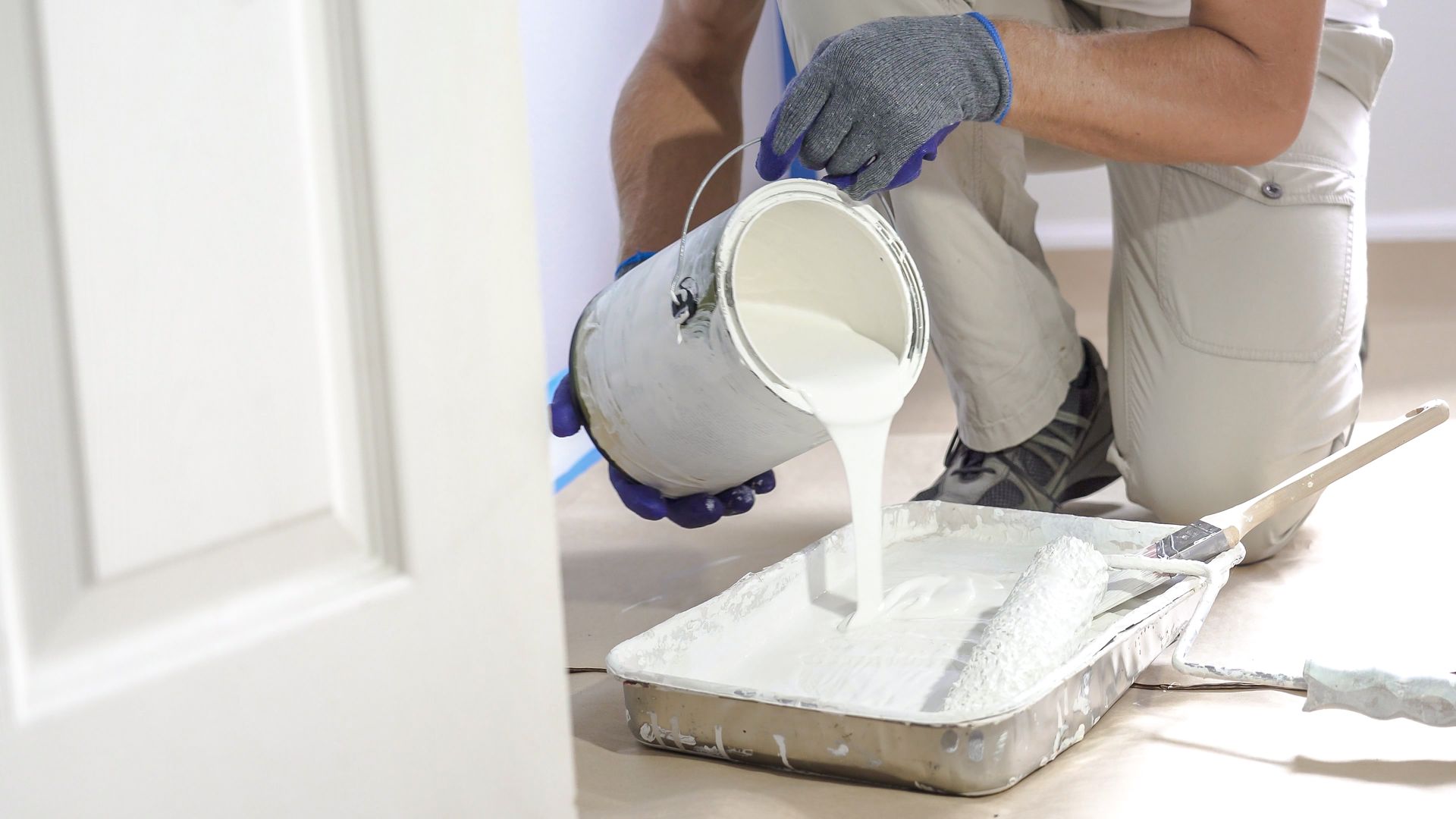 A professional from Mickey Wall Painting pours paint into a tray and dips a roller for residential interior painting services.