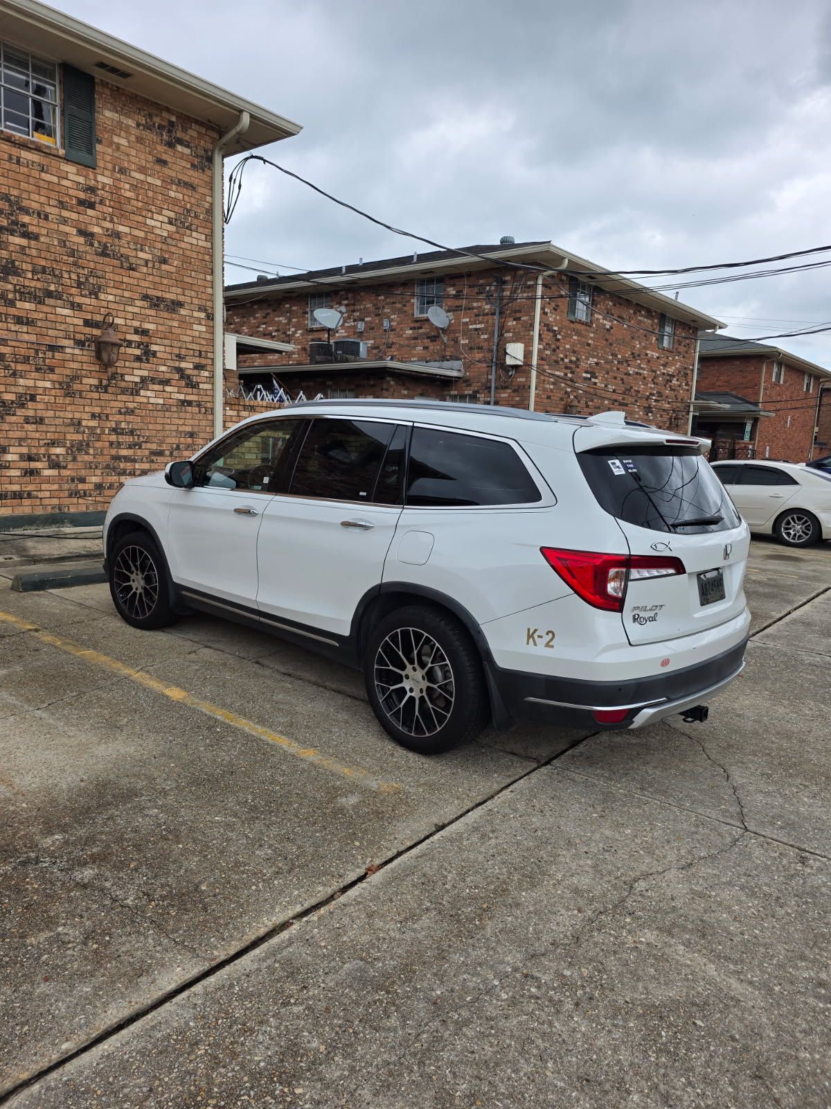 White Honda Pilot SUV parked between brick buildings.