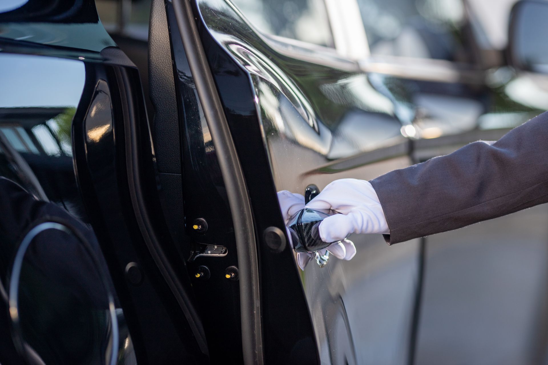A person is opening the door of a black car.