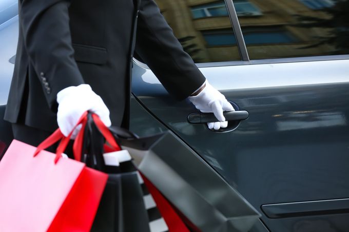 A man in a suit and white gloves is opening a car door