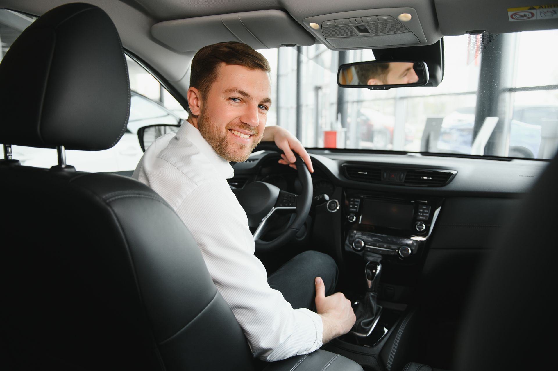 A man is sitting in the driver 's seat of a car and giving a thumbs up.